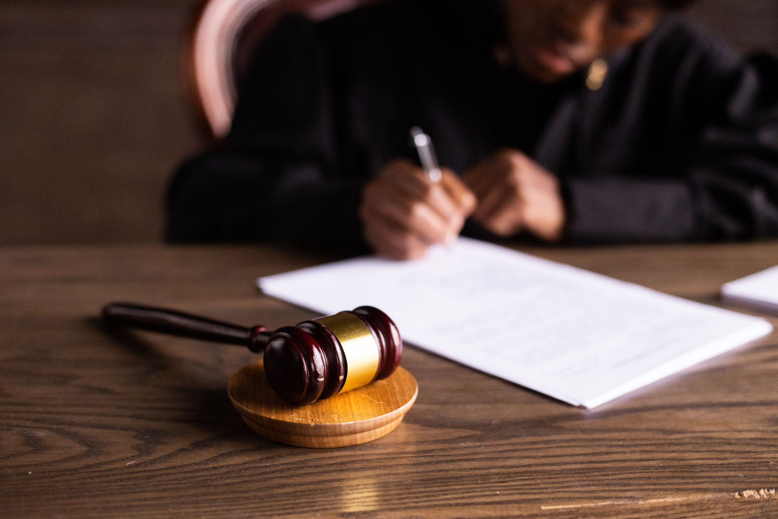 Judge signing legal documents at a desk with a gavel in the foreground, representing lengthy court proceedings
